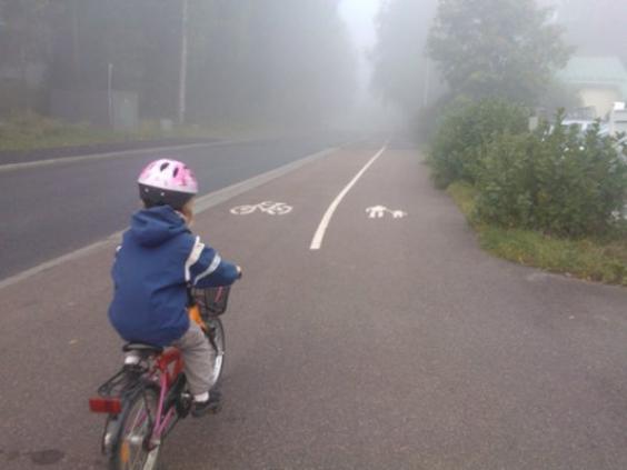 En barn cyclar på dimmig väg.